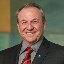 Donald Taylor, smiling man with fair hair, wearing a dark suit.